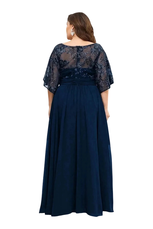 Woman wearing a black evening gown with lace details in a decorated room.