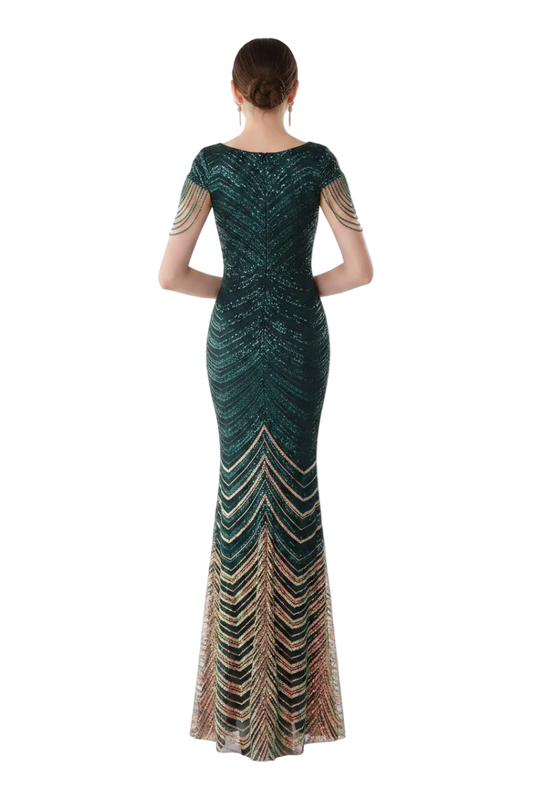 Woman in a long, dark green dress with multicolor pattern standing in front of a mirror.