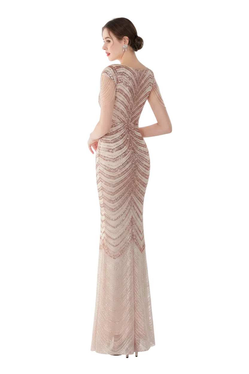 Woman in a long, elegant dress standing in front of a mirror in a softly lit room.