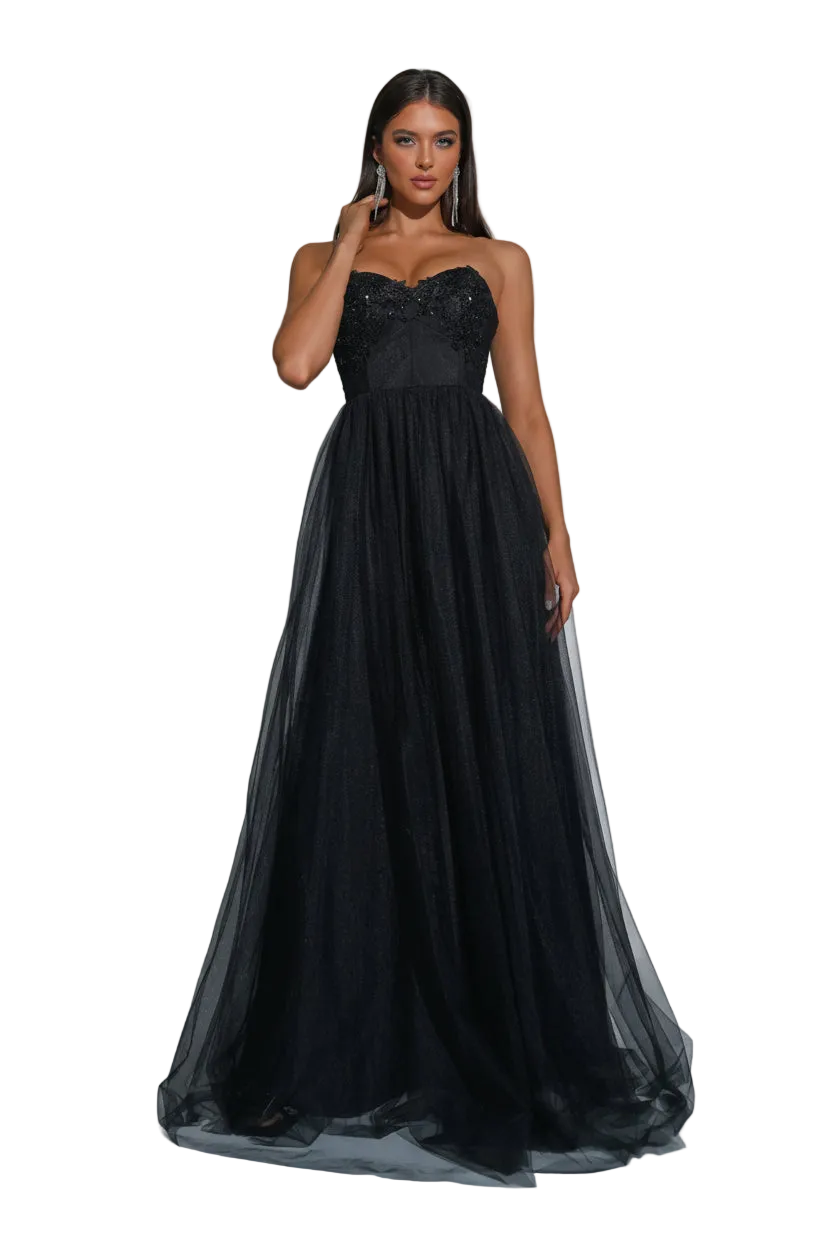 A woman models a strapless black formal gown with a fitted lace bodice and a voluminous tulle skirt, standing in a studio with spotlighting and silver disco balls at the corners.