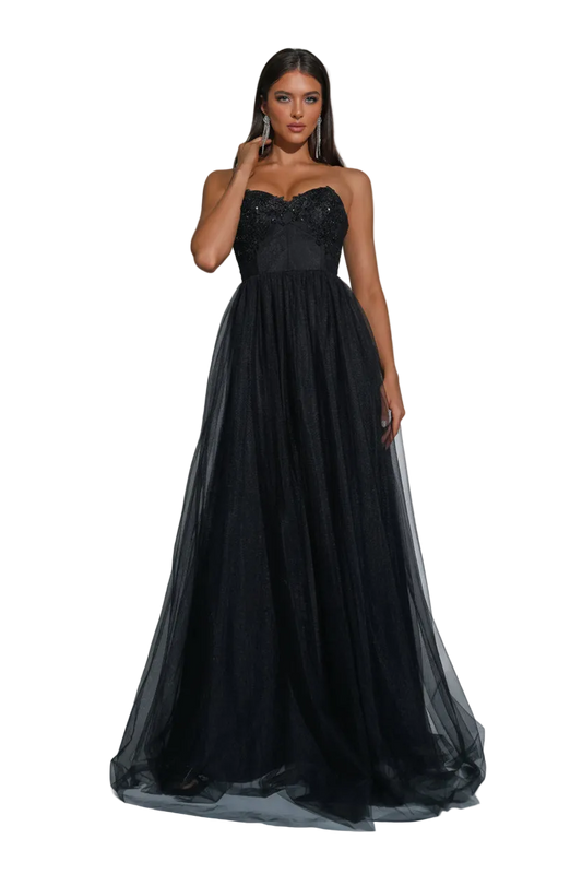 A woman models a strapless black formal gown with a fitted lace bodice and a voluminous tulle skirt, standing in a studio with spotlighting and silver disco balls at the corners.