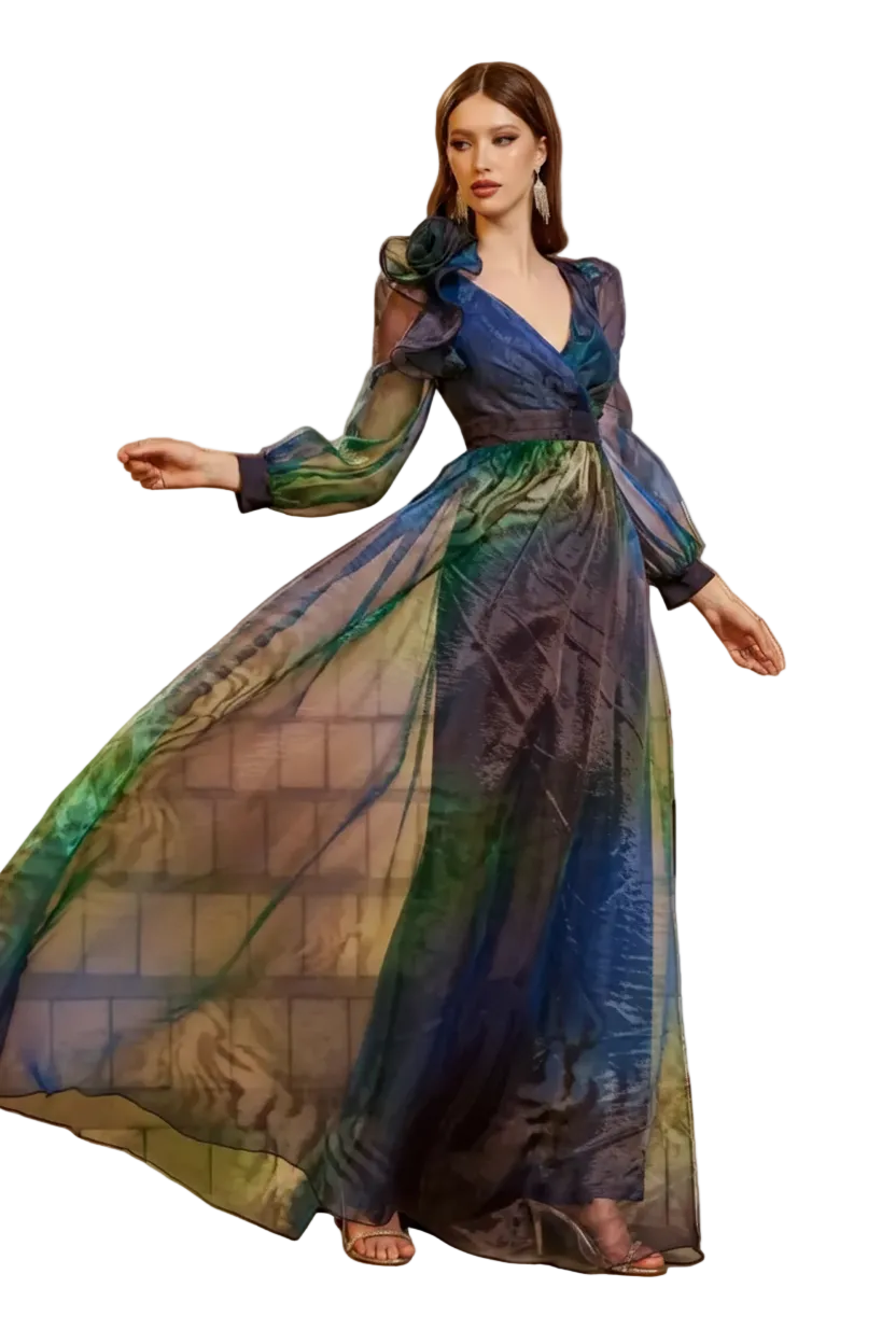 A woman models a flowing maxi dress with a blue, green, and purple gradient pattern on stone stairs. The dress features long sheer sleeves, a V-neckline, and a ruffled shoulder detail.