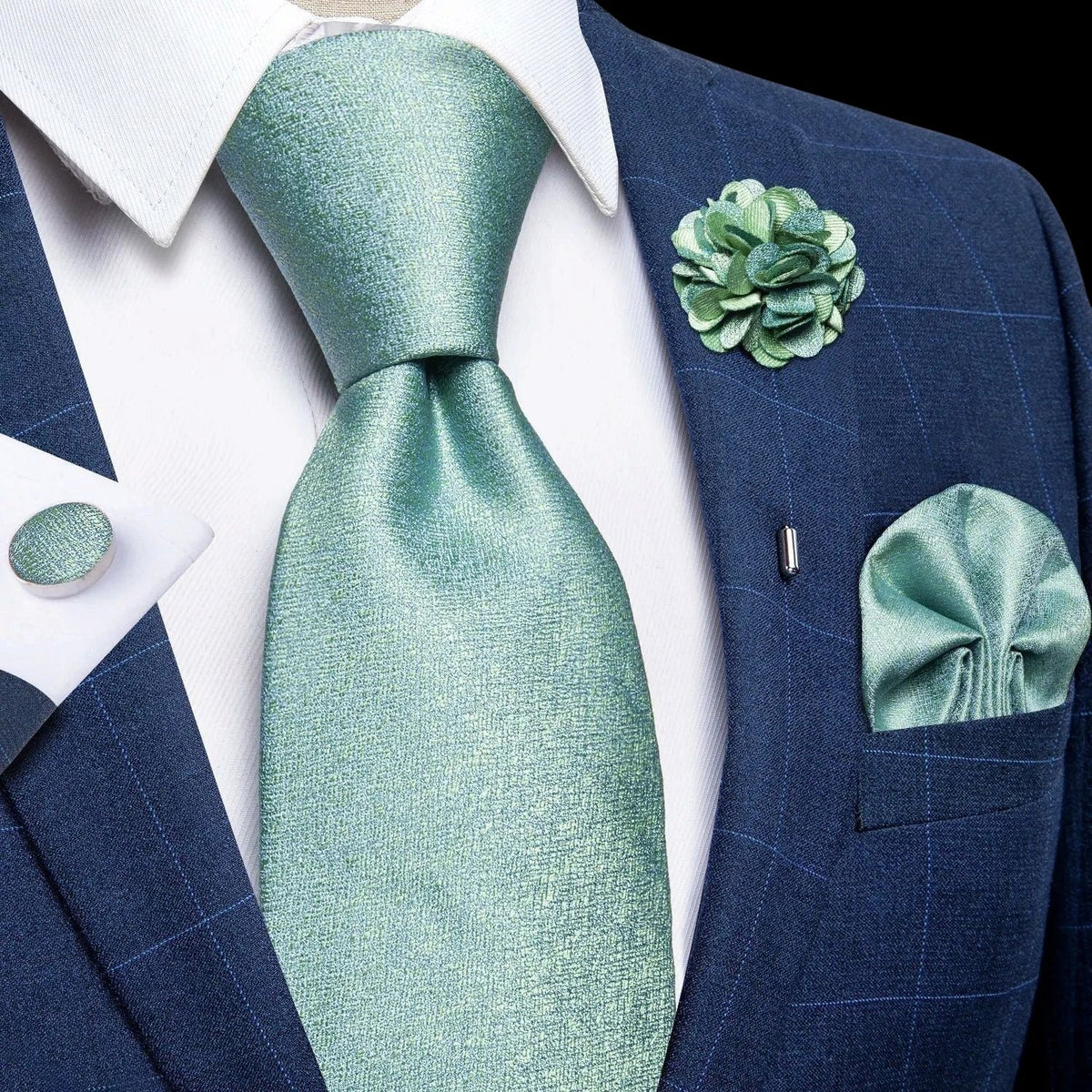 JASE HEART GLOBAL mint green silk necktie set with matching pocket square, lapel flower, and cufflinks on a blue suit
