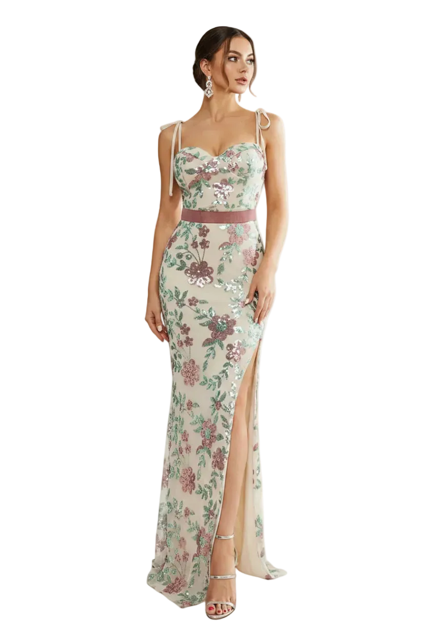 Woman wearing a floral evening gown in a bright room with large windows.