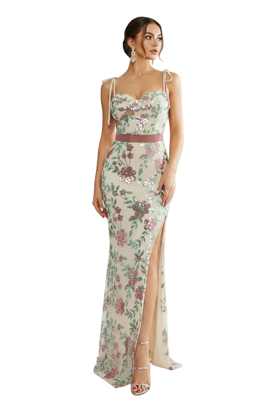 Woman wearing a floral evening gown in a bright room with large windows.