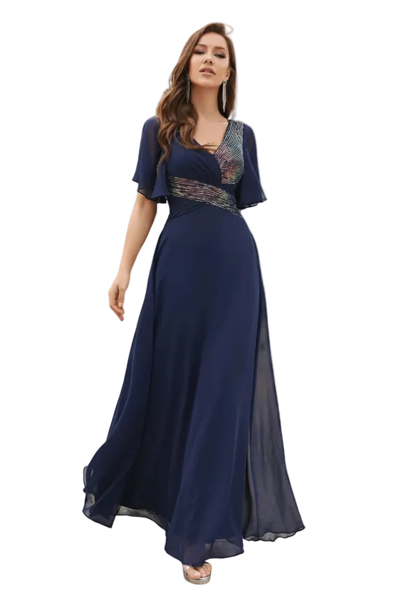Woman in a long navy blue dress standing outdoors with palm trees and a pool in the background.
