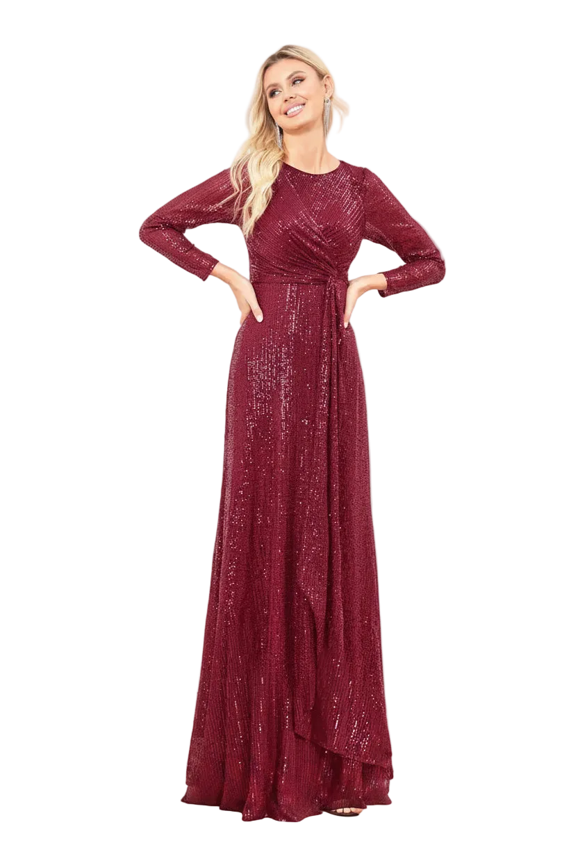 A woman modeling a floor-length burgundy maxi gown with long sleeves, a crew neckline, and a shimmering sequined texture against a plain white background.