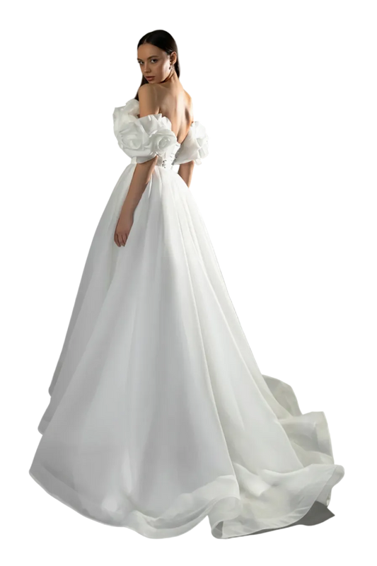 A woman modeling an off-the-shoulder white wedding gown with voluminous ruffled sleeves and a full flowing skirt, photographed against a dark gray studio background. A watermark reading 'ADLN Official Store' appears across the lower part of the dress.