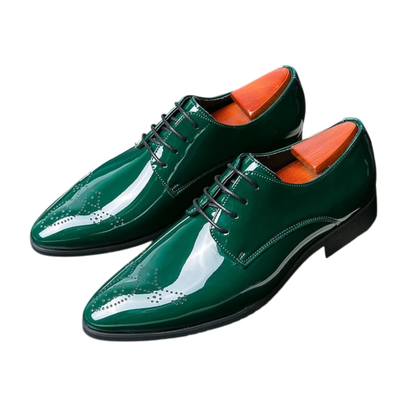 A pair of glossy dark green oxford dress shoes with wingtip brogue detailing, black laces, and bright orange interior lining, displayed on a dark surface with a decorative bow tie prop.