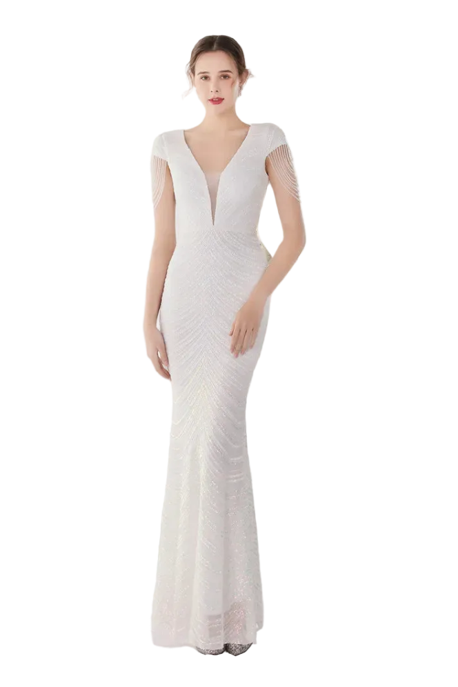 Woman wearing a white evening gown in a softly lit room with a mirror.