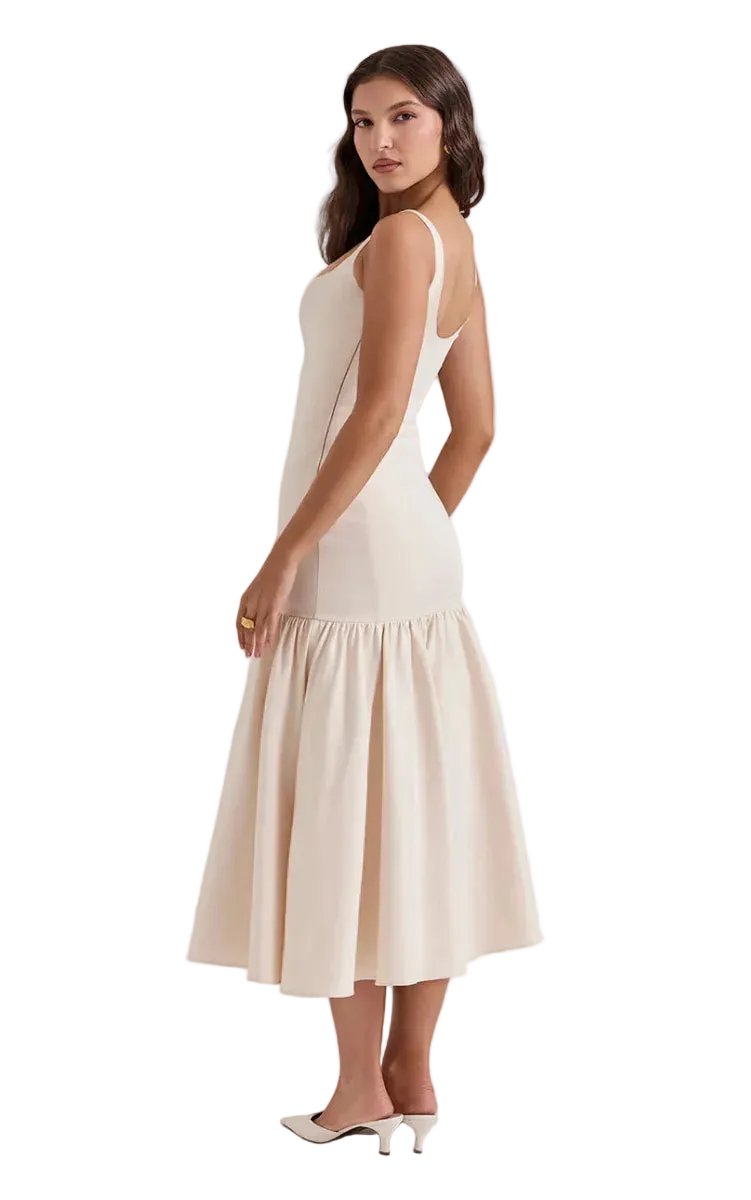 A woman modeling a sleeveless, off-white midi dress with a flared skirt, shown from a side-back angle against a solid white background.