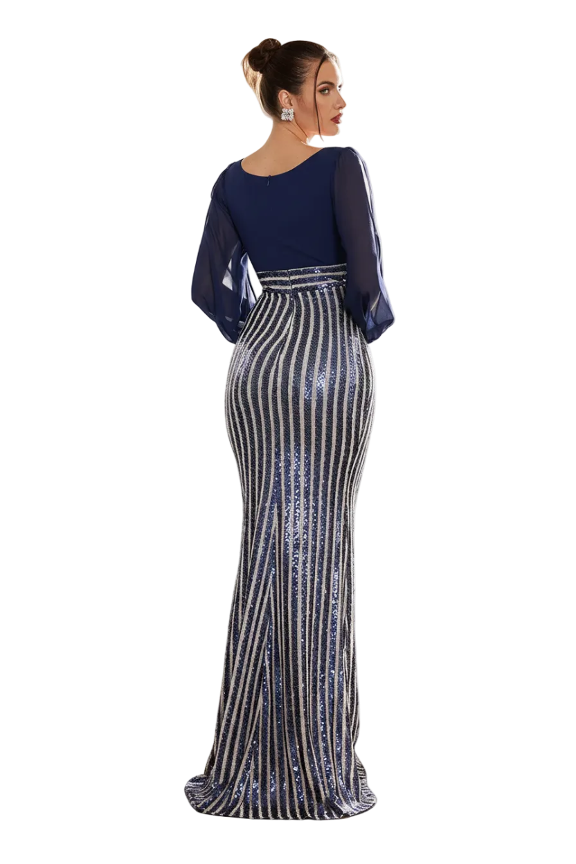 A woman models a floor-length navy blue evening gown with a high-waisted, vertically striped sequined skirt in a sunlit indoor setting with a wooden honeycomb screen and a striped armchair.