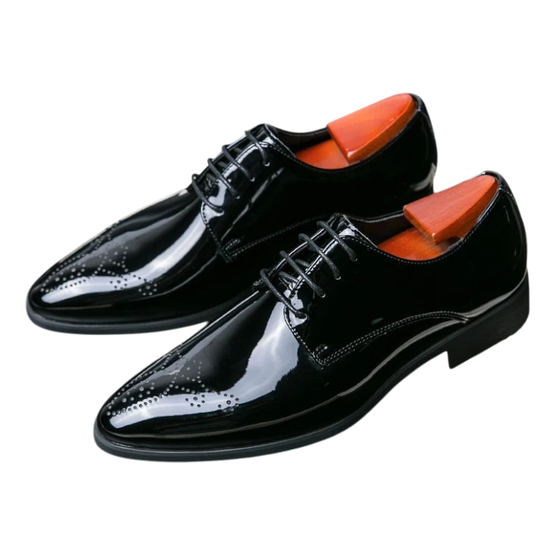 A pair of men's black patent leather oxford dress shoes with brogue detailing, displayed on a black surface inside a white frame. The shoes are shown from a high angle, revealing bright orange insoles.