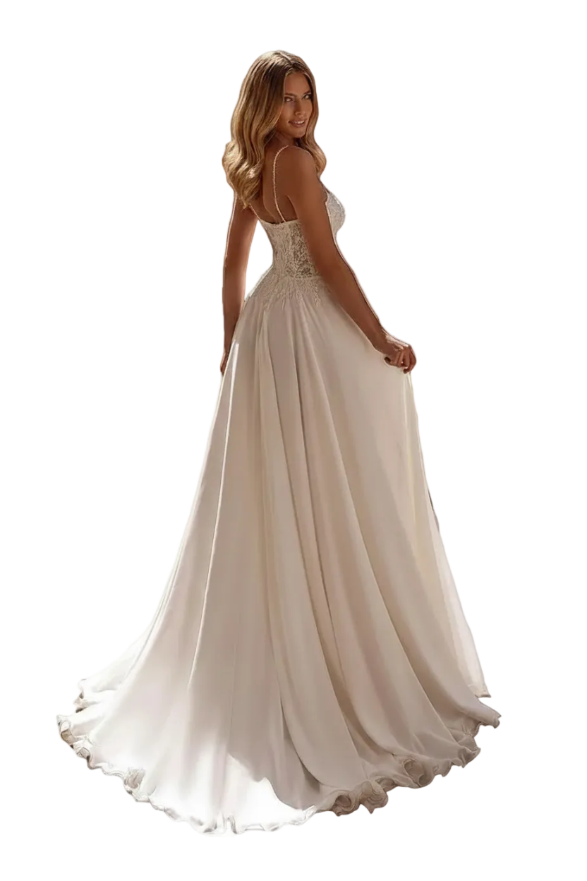 A woman wearing a white A-line wedding dress with a backless open back and lace bodice, photographed outdoors on a stone walkway near a building entrance. The dress has thin straps, a fitted bodice, and a full flowing skirt with a slight train.