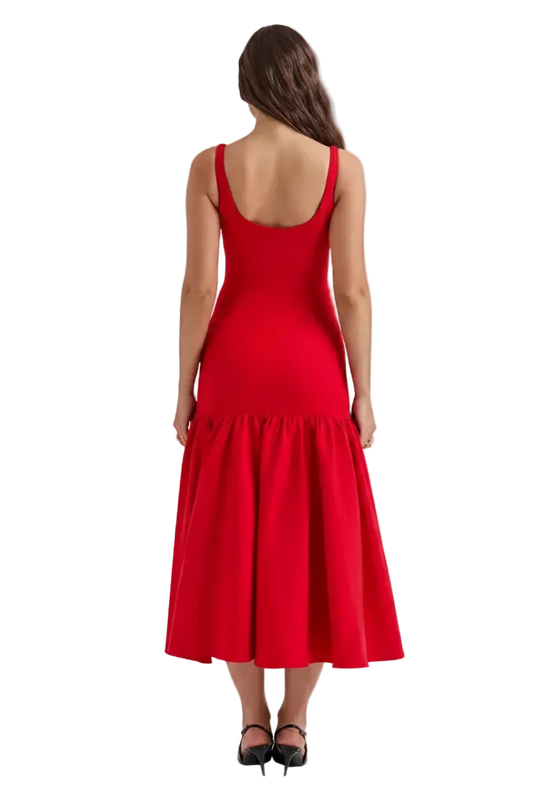 A woman viewed from the back wearing a sleeveless bright red midi dress with a wide flared skirt and black heels, isolated on a solid black background.