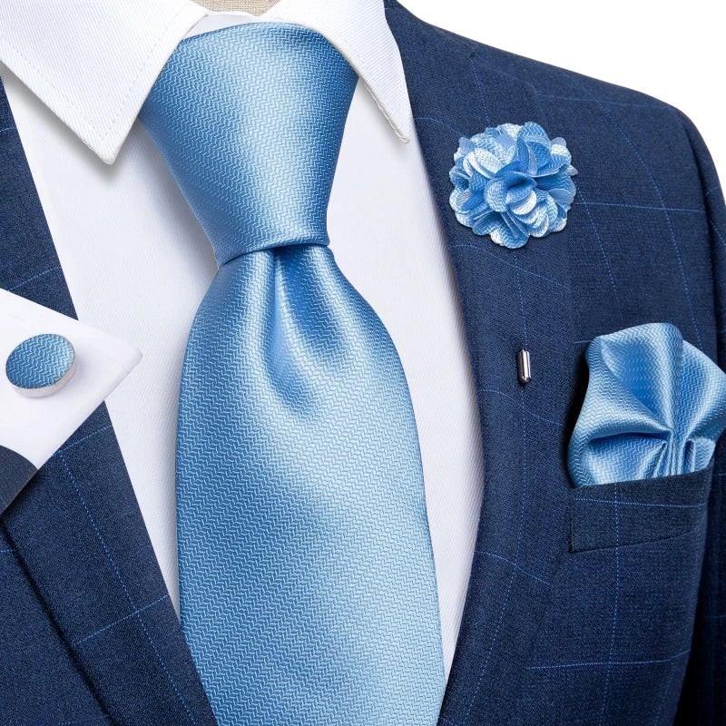 JASE HEART GLOBAL light blue silk necktie set with matching pocket square, lapel flower, and cufflinks on a navy suit