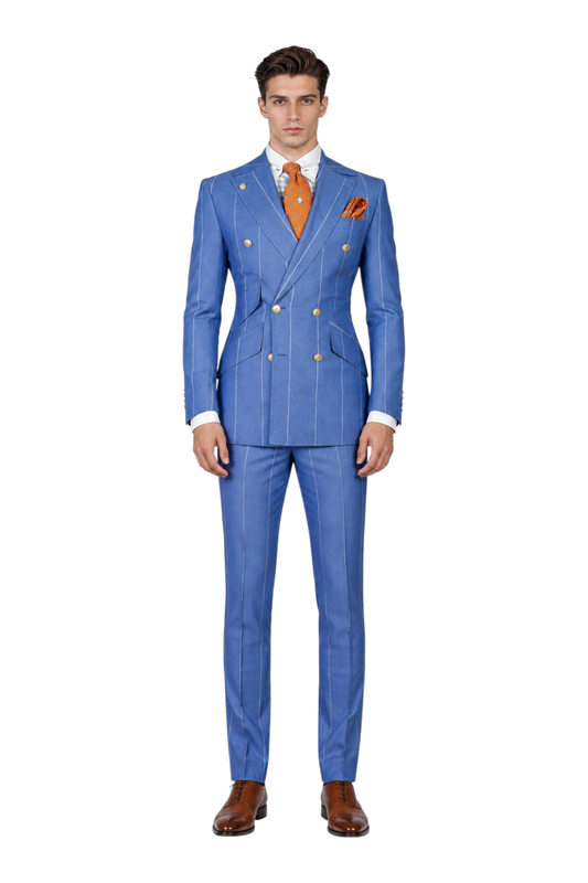 A man modeling a blue double-breasted pinstripe suit with gold buttons, a white shirt, an orange patterned tie, and an orange pocket square, set against a textured light gray background with a 'UA' logo in the top left corner.